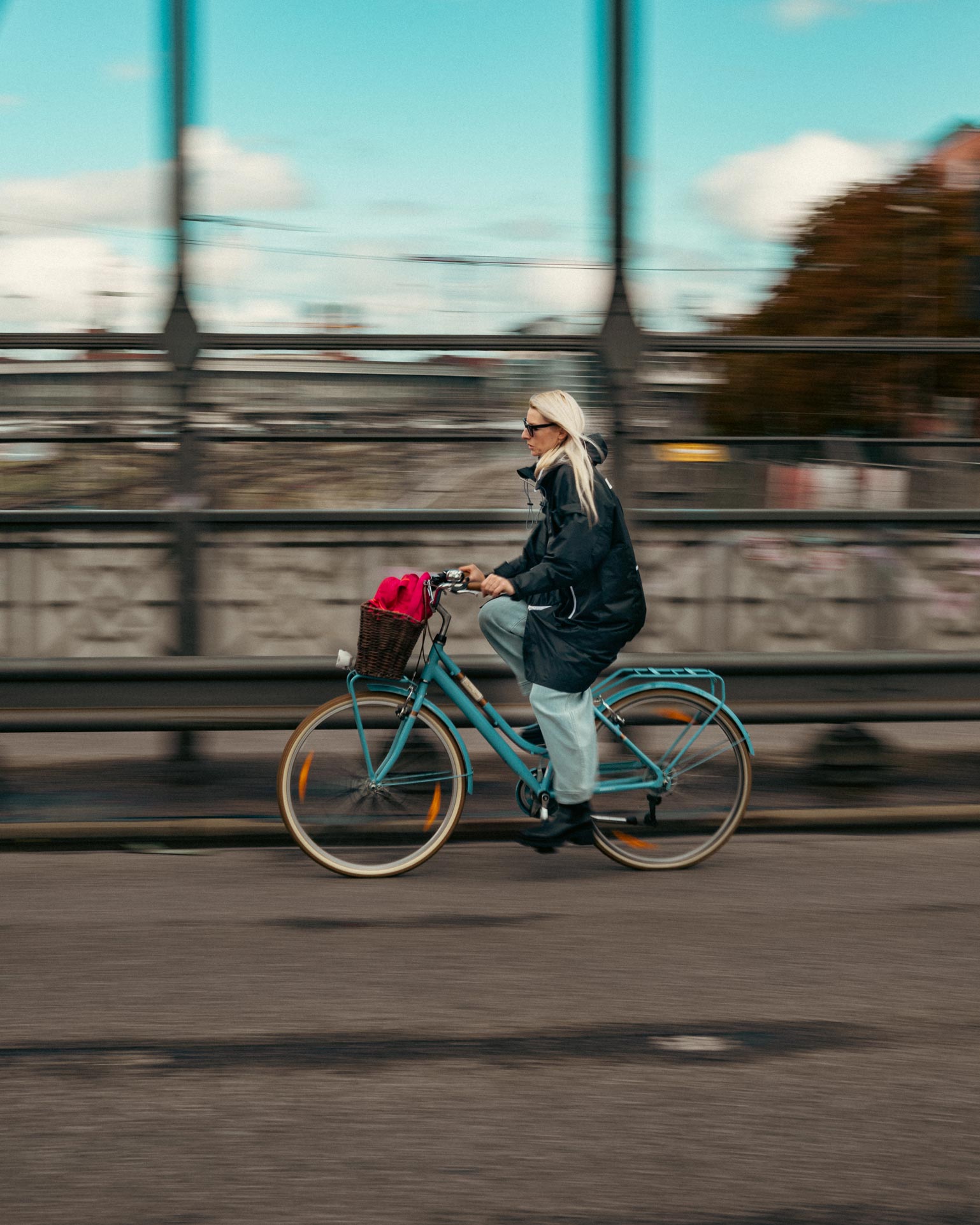 Motion blur photograph of a woman cycling with a turquoise bike