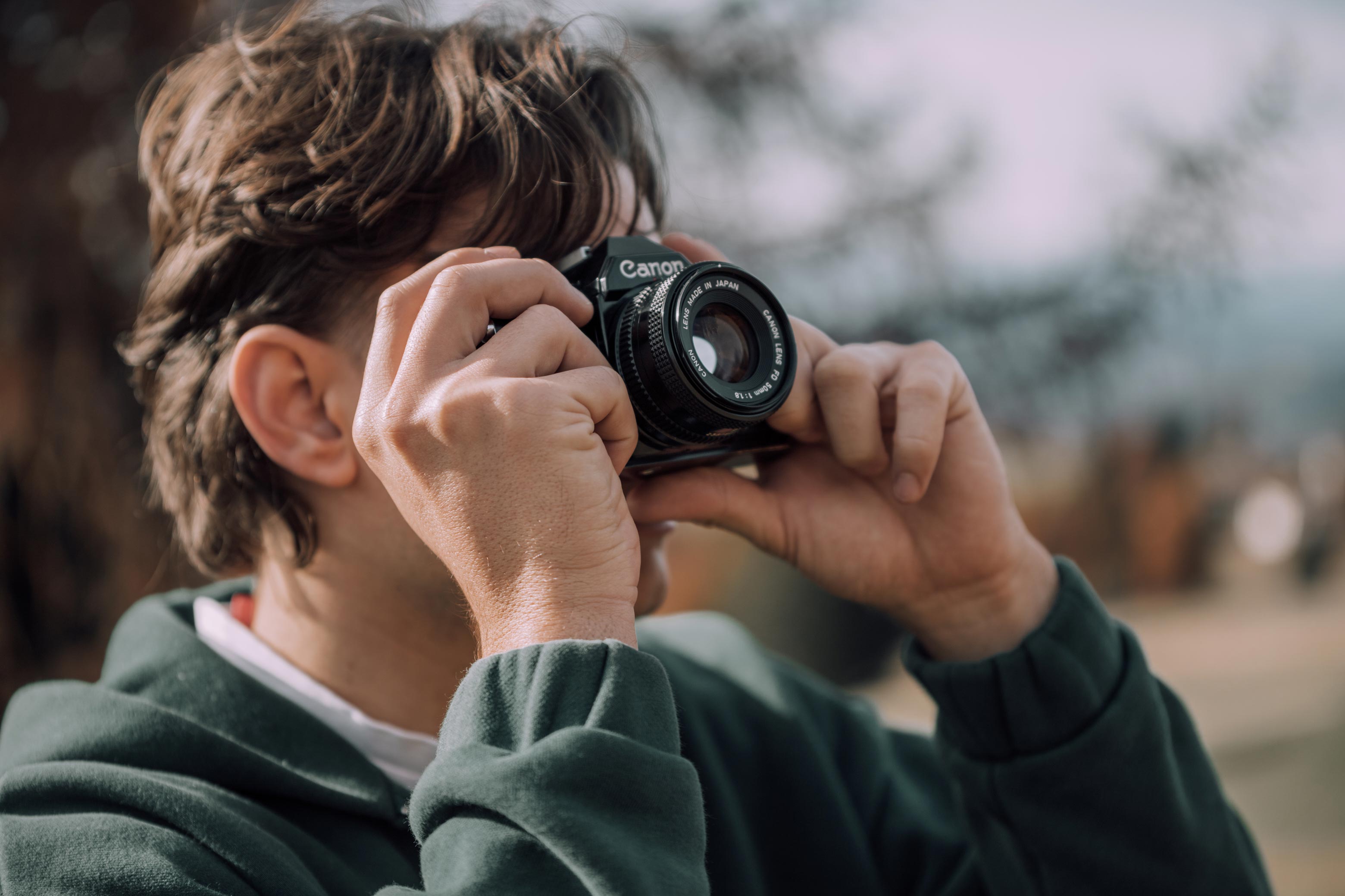 young man taking a photo with a canon ae-1