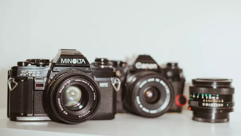 Minolta X-700 in sharp focus in the foreground, Canon AE-1 blurred in the background — two analog film cameras