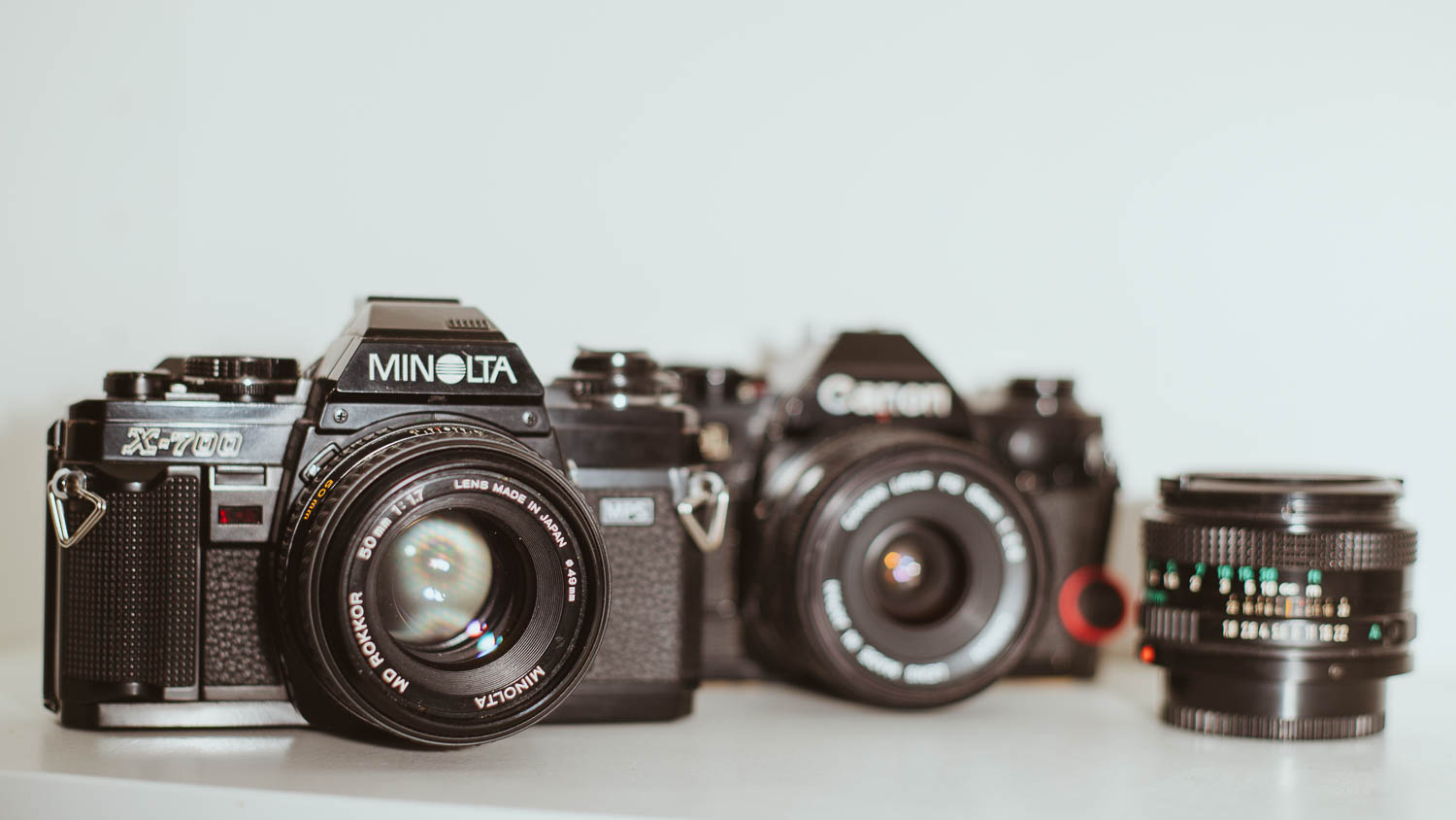 Minolta X-700 in sharp focus in the foreground, Canon AE-1 blurred in the background — two analog film cameras