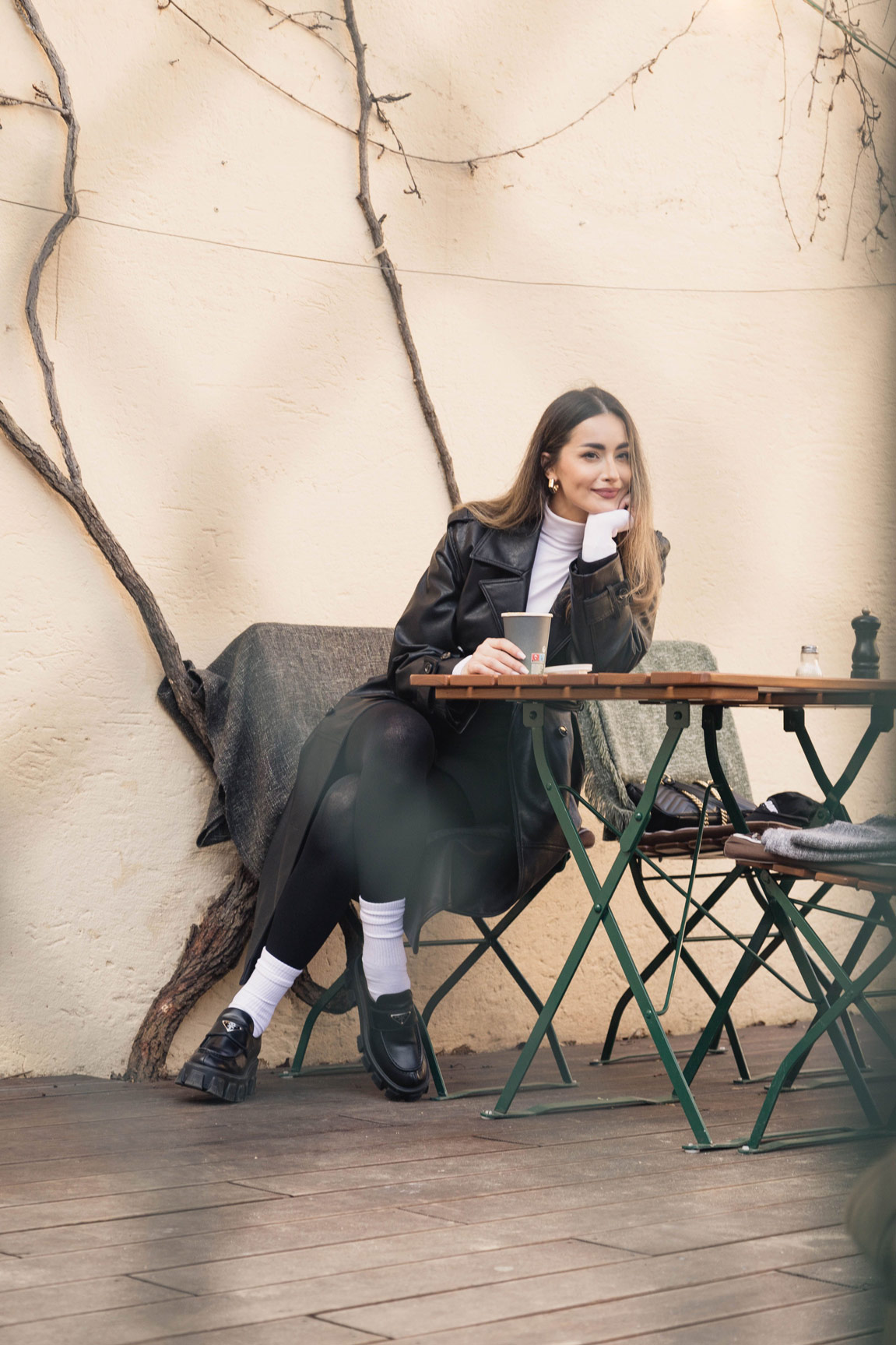 Woman in a leather jacket sitting at an outdoor café table