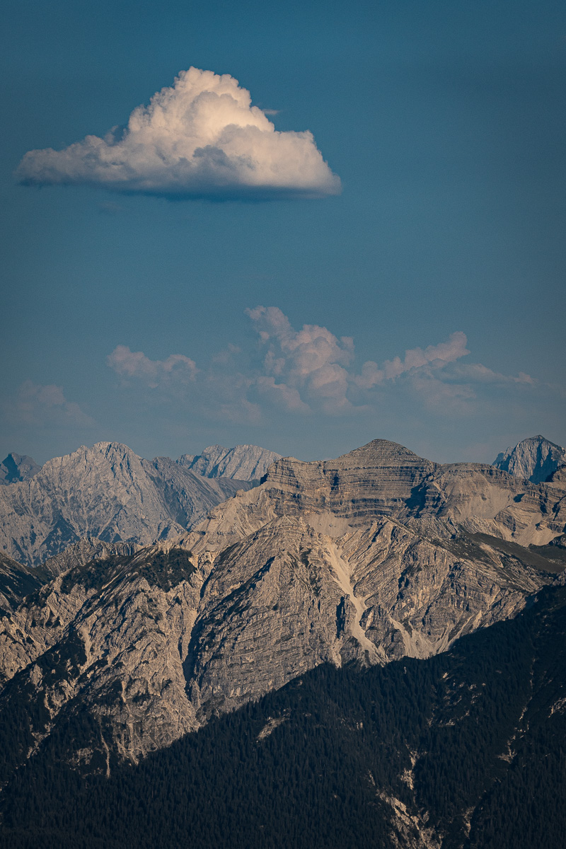 Single cloud above a rugged mountain range in daylight
