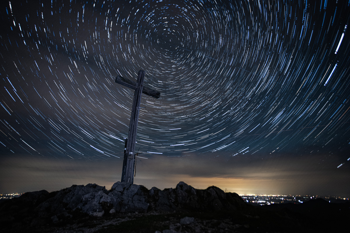 Star trails circling the summit cross on the Krottenkopf at night