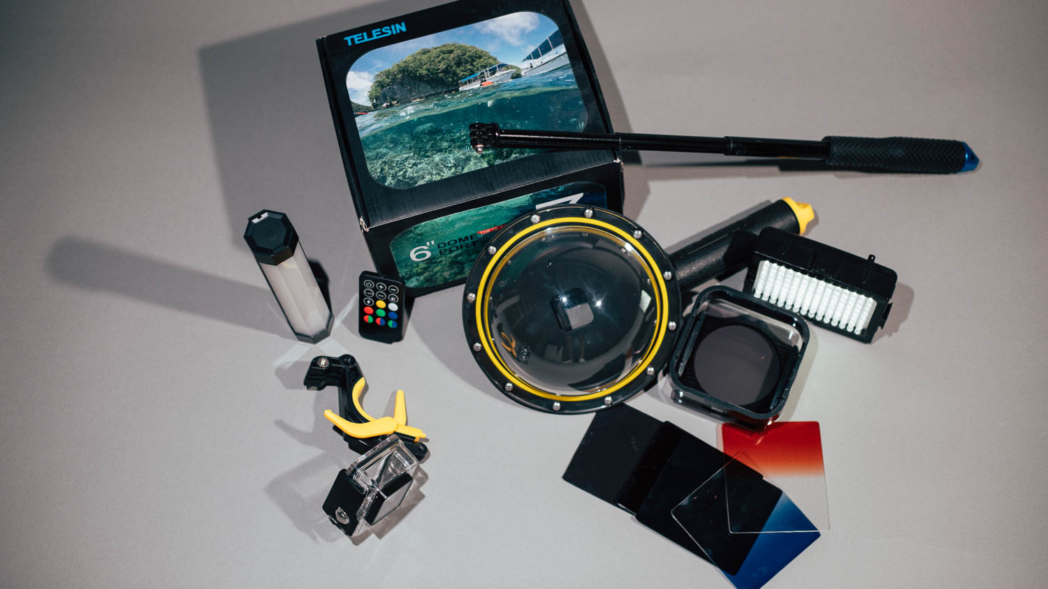 GoPro dome port, remote control, LED light and ND filters — unused photography equipment on a table