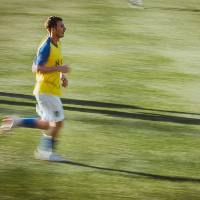 Panned shot: running player with a sharp face, body and grass blurred