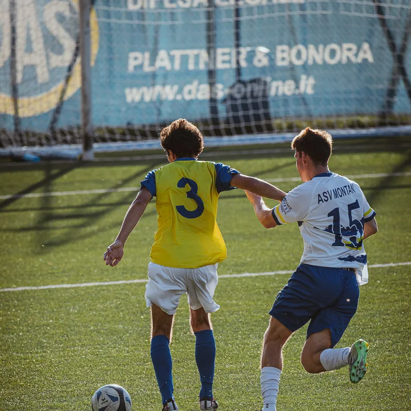 Player number 3 and an opponent seen from behind, their shadows on the pitch