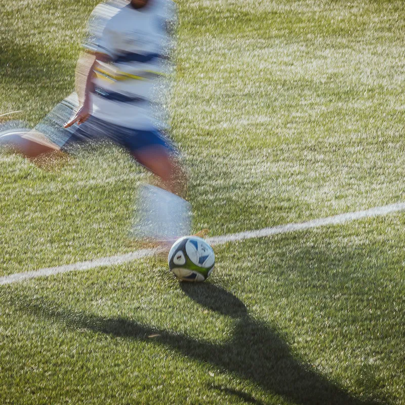 Panned shot: player taking a free kick, blurred player, sharp ball