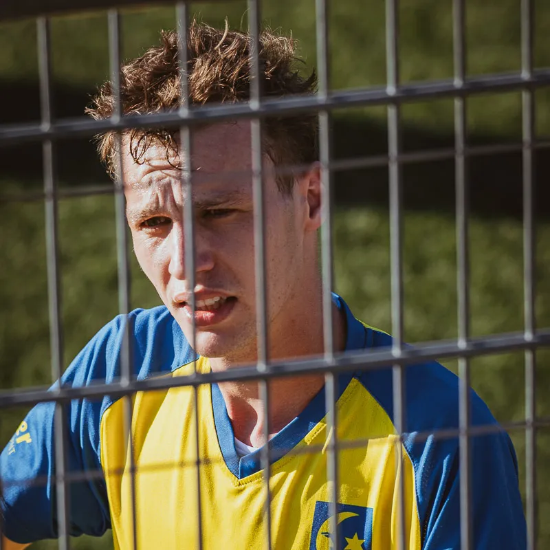 Player behind a metal fence, looking to the side