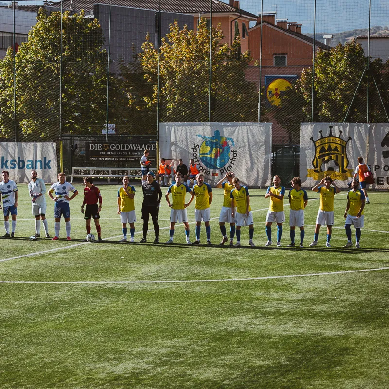 Both teams lined up before kick-off, trees and houses in the background