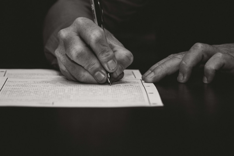 close-up of a man signing a document with a ballpoint pen