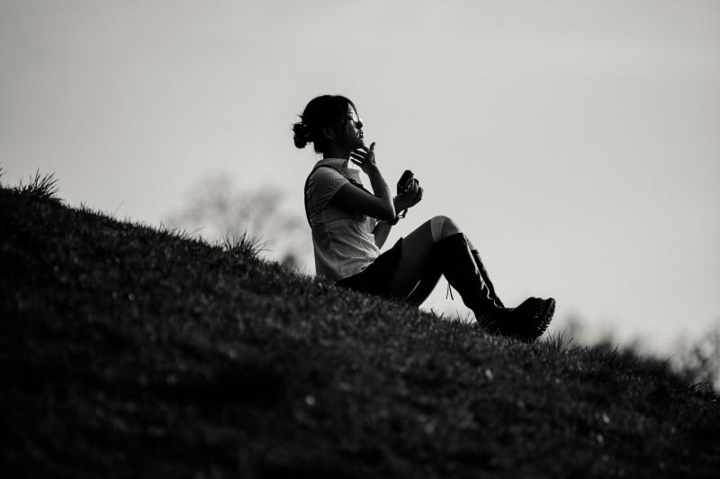 A woman is sitting in the sun on the Olympiaberg in Munich
